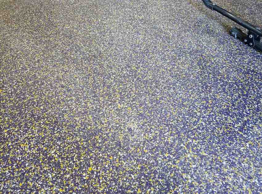 Asphalt surface covered with numerous small yellow petals; a scooter is visible in the top-right corner.